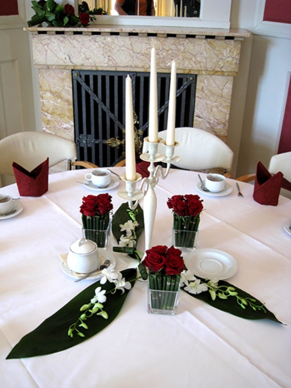 Tischschmuck: vier Vierecksgläser mit roten Rosen